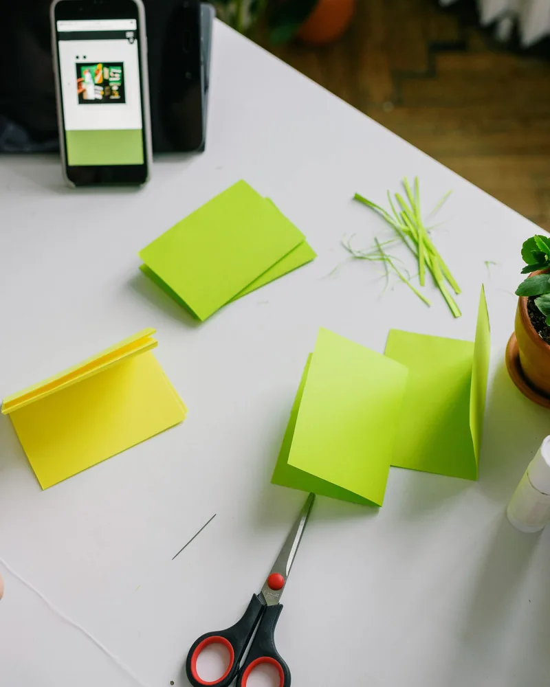Mesa de trabajo con recortes de papel de colores, tijeras y piezas en preparación para una maqueta